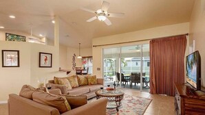 A spacious living room with a sofa, coffee table, and a TV on a wooden stand. - Casa Pura Vida pool home with three bedrooms plus (Cape Coral)