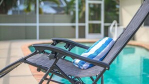 A poolside lounge chair with a towel. - Casa Pura Vida pool home with three bedrooms plus (Cape Coral)