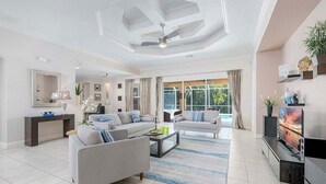 Ein geräumiges Wohnzimmer mit großem Fernseher, zwei Sofas, einem Couchtisch und einem Deckenventilator.