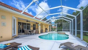 Ein Außenpool mit Liegestühlen und einer überdachten Terrassenfläche.