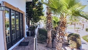 A hotel entrance with a covered patio, palm trees, and a view of the street.