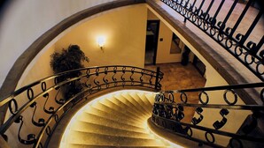 A spiral staircase with ornate metal railings and a light fixture at the top.