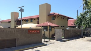 A residential building with a red-tiled roof, a gated entrance, and a sign that reads "ITAOCa residence". - Beachfront apartment on Itamaracá Island/PE - Itaoca Residence Condominium (Ilha de Itamaracá)