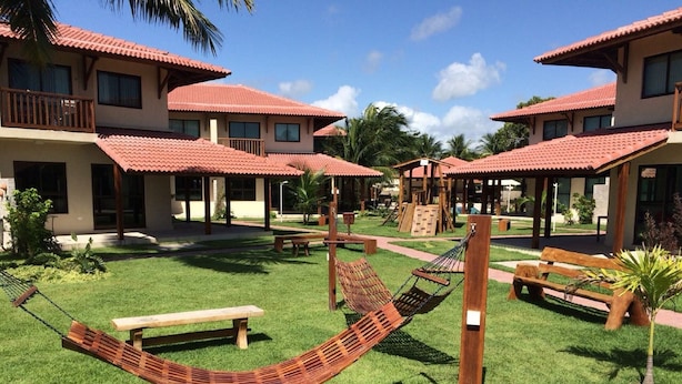 A resort with multiple buildings, outdoor seating, and a hammock in the yard. - Beachfront apartment on Itamaracá Island/PE - Itaoca Residence Condominium (Ilha de Itamaracá)