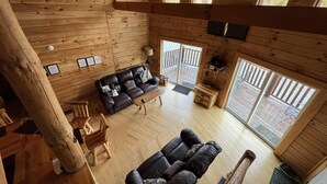 Une cabine spacieuse avec un intérieur en bois, un canapé, une table à manger et une vue sur l’extérieur grâce à de grandes fenêtres.