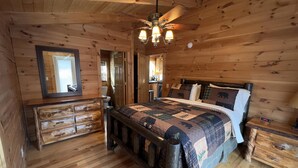 Une chambre dans une cabane en bois, avec un lit, une commode et une table de chevet.