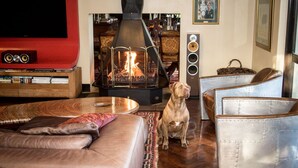 Una sala de estar con chimenea, muebles de cuero y televisión.