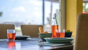 Une table dressée avec une tasse de thé, une bouteille, un bol de pain et une assiette contenant une salade.