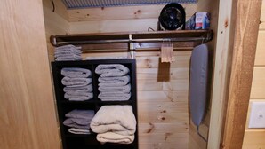 A wooden interior with a shelf holding folded towels and a laundry basket.