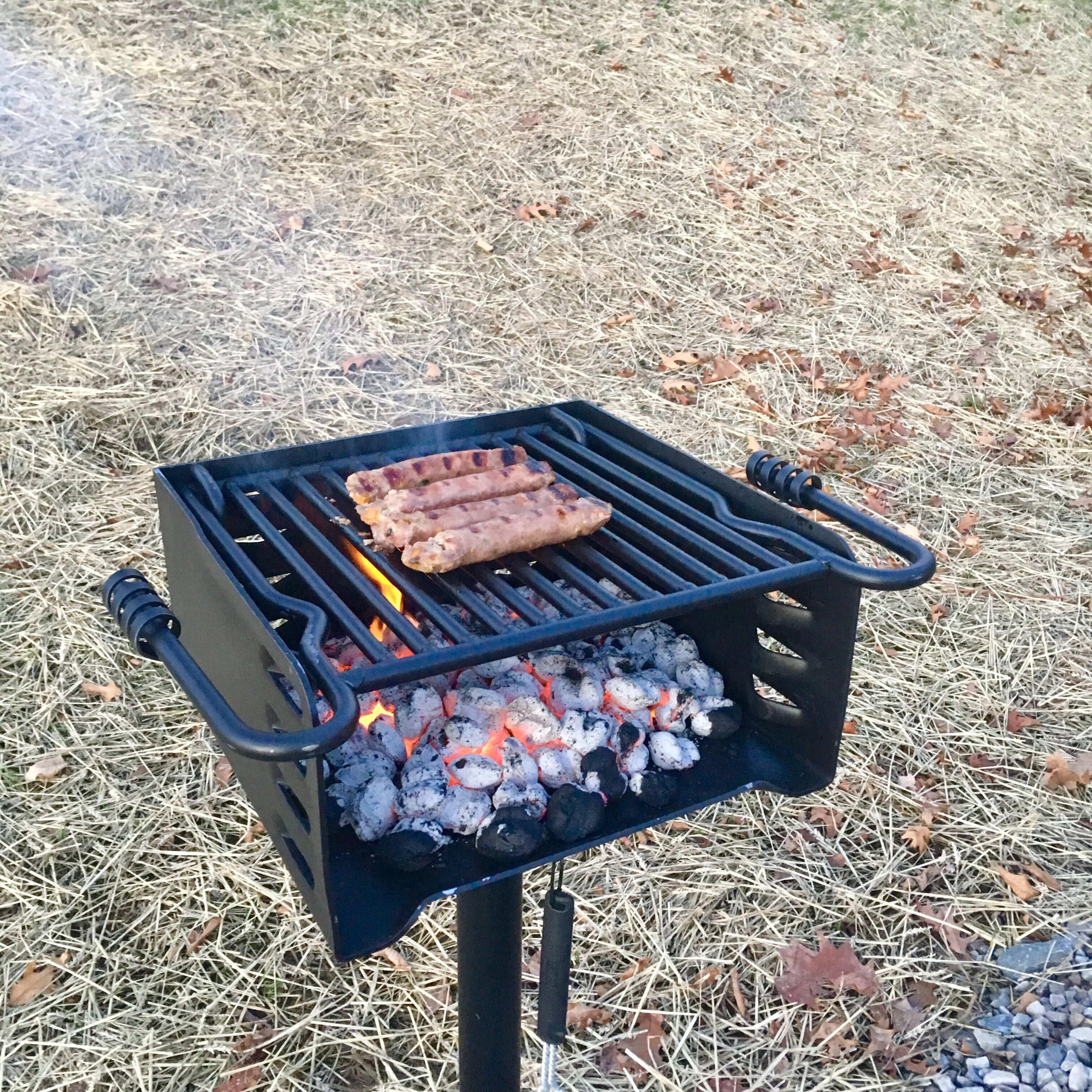 En portabel grill med korvar som tillagas över kol.