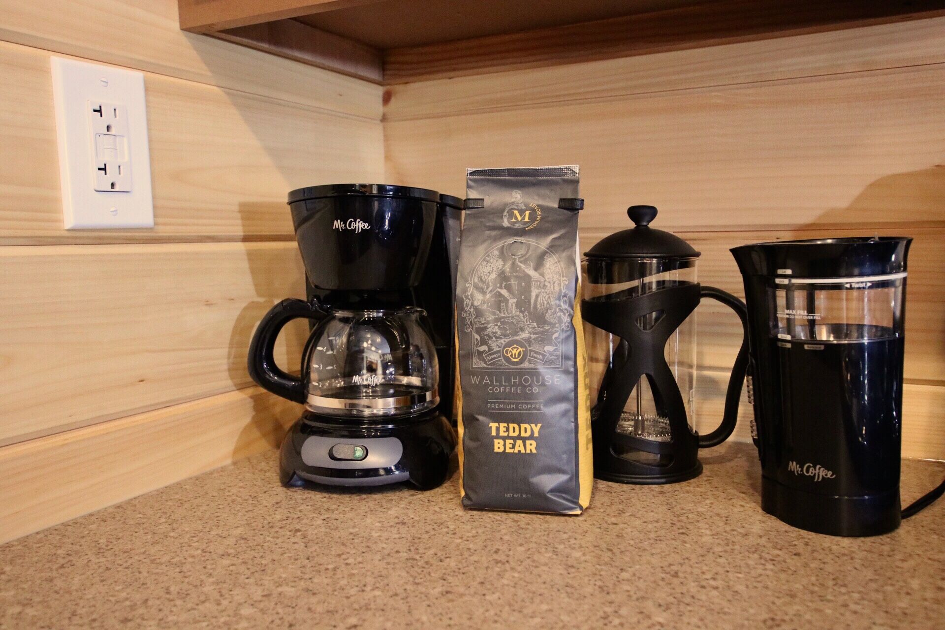 A coffee maker, a coffee bag, and a coffee pot on a kitchen counter.