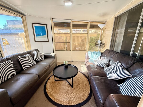 A living room with two brown leather sofas, a round black coffee table, and a woven rug.