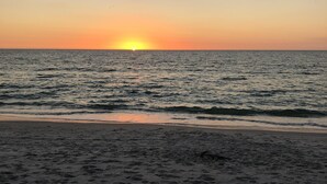 A beach with footprints leading to the water, a calm sea, and a sunset in the distance. - Secluded and Private House with Pool, Near Beach.  11 blocks from Village. (Boca Grande)