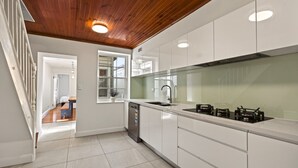 A modern kitchen with white cabinetry, a wooden ceiling, and a view into the adjacent bedroom. - Waterview terrace in rock (Millers Point)