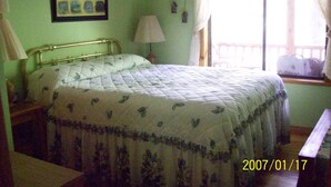 A bedroom with a bed, a nightstand, a lamp, and a window with curtains. - Sanitized! Creekside Cottage sits over Creek  Woods, Looking into Park!  Pets OK (Cosby)