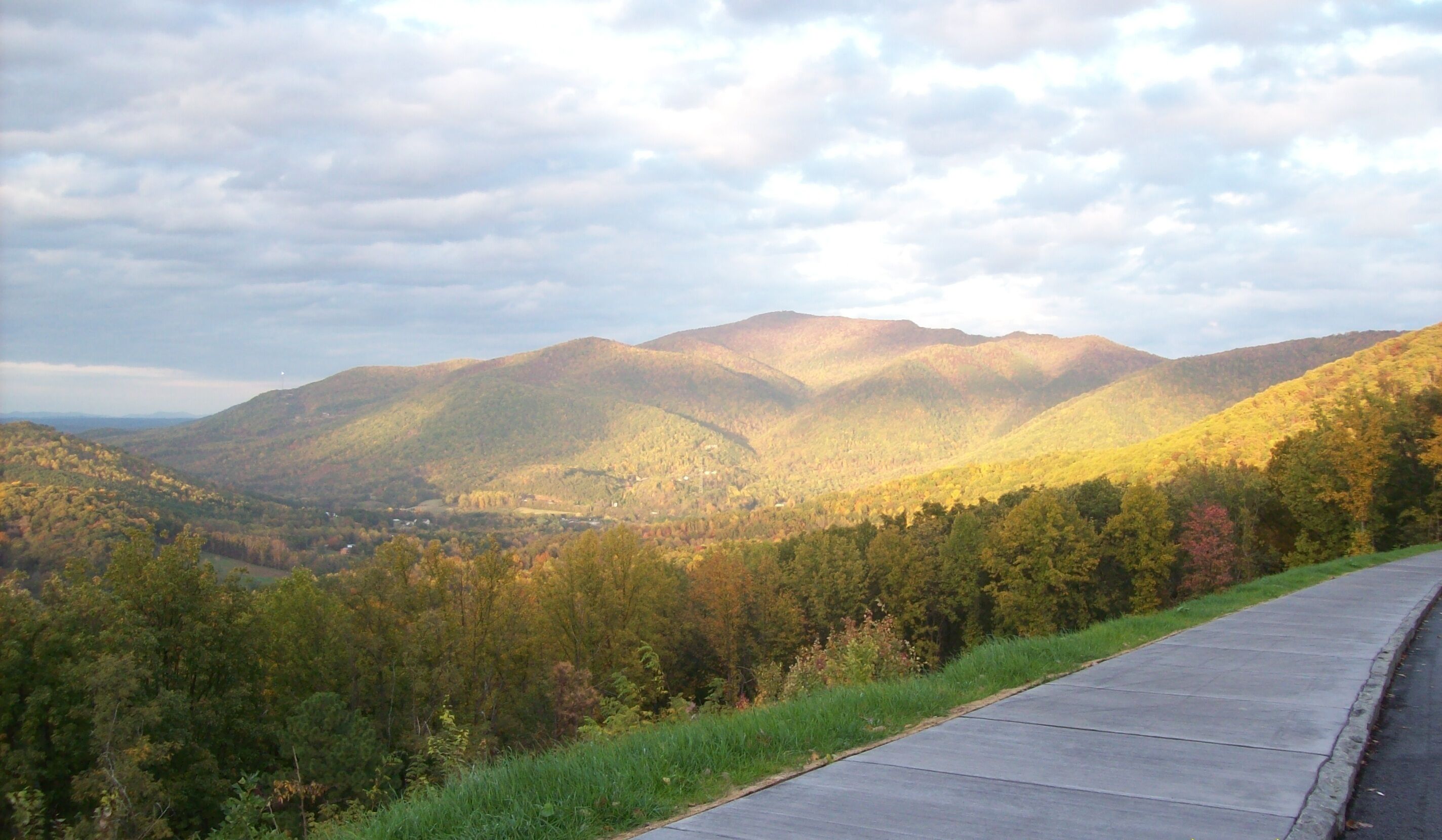 Una carretera pavimentada con vistas a colinas ondulantes y un cielo nublado.