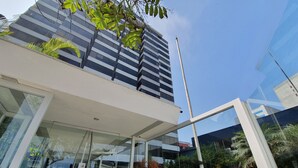Un edificio moderno con fachada de vidrio, techo plano y un jardín bien cuidado con diversas plantas y un camino.