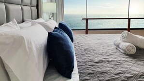 Una habitación de hotel con una cama grande, vistas al océano y un balcón.
