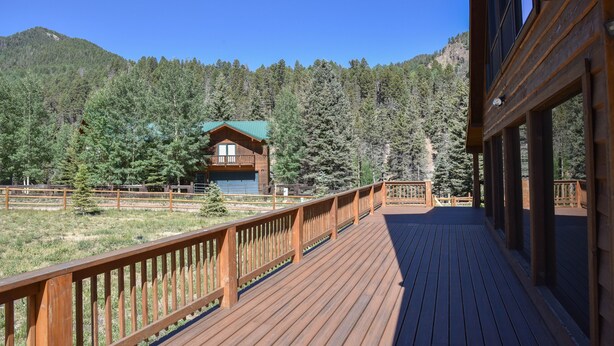 A wooden deck with a view of a mountain and forest. - GORGEOUS Home with Mtn Views/Perfect For Families & Groups/Wrap Porch/ATV Pking (Red River)