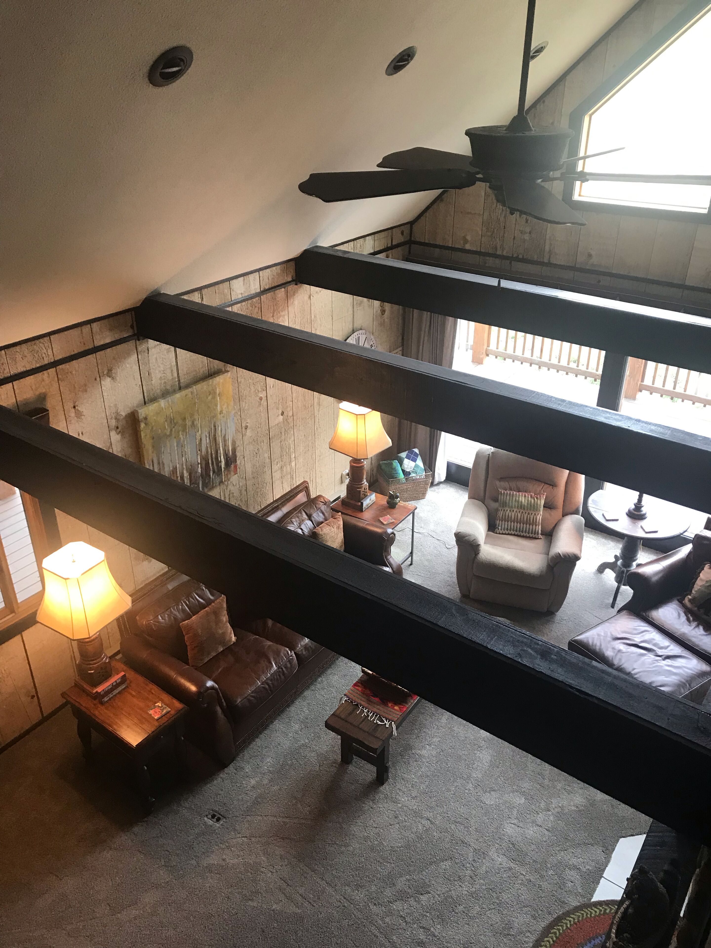 Une pièce de style « loft », avec un plafond haut, des poutres apparentes, un ventilateur de plafond et une grande fenêtre qui laisse entrer la lumière naturelle.