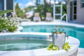 Un espace aménagé au bord de la piscine, avec un seau en métal contenant des bouteilles, probablement remplies de boissons, et quelques pétales de fleurs éparpillés.