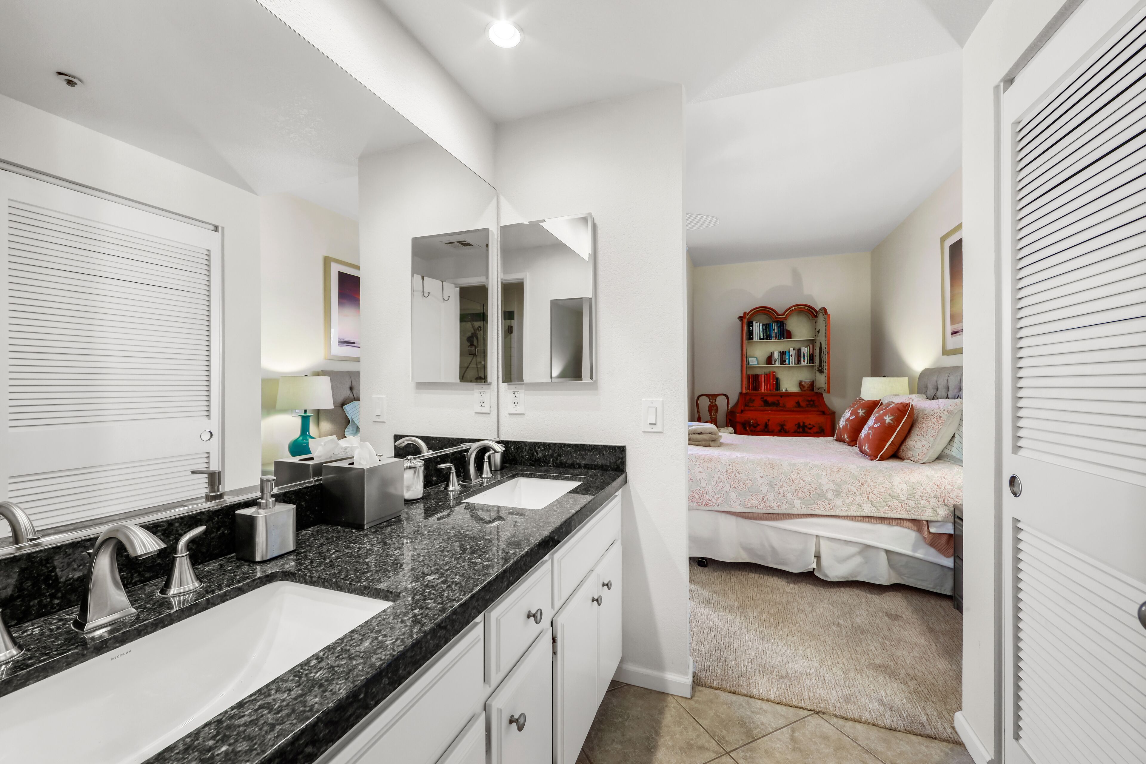 A modern bathroom with a double sink, large mirror, and a walk-in closet.