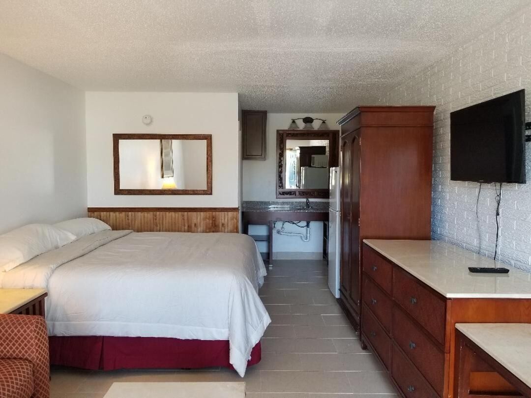 Une chambre d’hôtel comprenant un lit, un bureau, une commode, un miroir et un téléviseur.