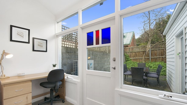 A home office with a desk, chair, and two framed certificates on the wall.