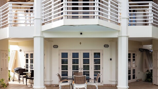 A two-story building with a swimming pool, outdoor seating, and a covered patio area.