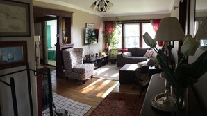 Ein Wohnzimmer mit Sofa, Sessel und einem Esstisch mit Blumenvase.