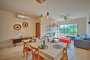 A dining area with a table set for four, chairs, and hanging pendant lights.