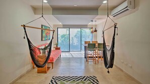 A spacious room with a large window, a dining area, and two hammocks. - Resort-Style Condo 3 Miles to Historic Tulum Ruins (Tulum)