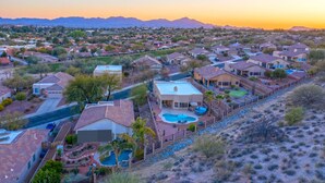 A residential area with houses, a swimming pool, and a desert landscape in the background.