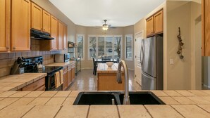 A kitchen with wooden cabinets, a stainless steel refrigerator, a microwave, and a dining area with a table and chairs.