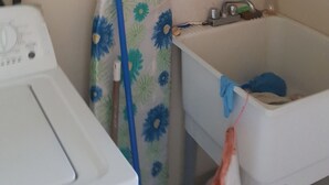 A laundry area with a washing machine, an ironing board with a floral cover, and a sink with a faucet. - AFFORDABLE ACCOMMODATION . VACATION SHORT OR LONG-TERM RENTALS . WELCOME TO ALL  (St. Michael)