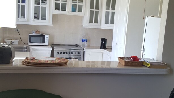 A kitchen with white cabinets, a microwave, a stove, and a sink. - AFFORDABLE ACCOMMODATION . VACATION SHORT OR LONG-TERM RENTALS . WELCOME TO ALL  (St. Michael)