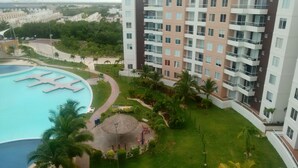 Un immeuble de grande hauteur doté d’une piscine, de palmiers et d’une pelouse bien entretenue.