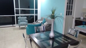 Un coin repas avec une table en verre, des chaises, un canapé et une plante en pot.