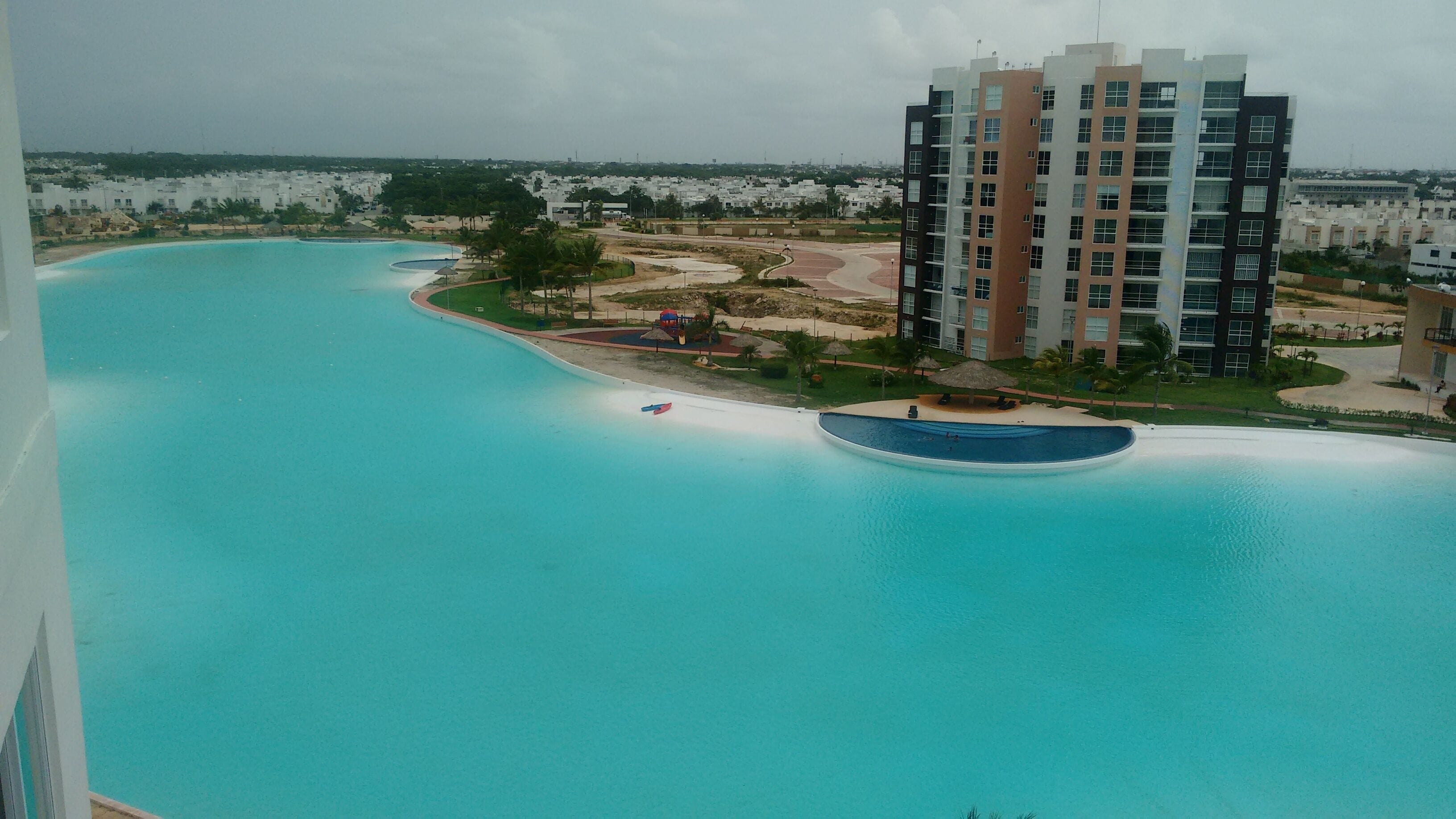 A high-rise building with a swimming pool and a beach area.