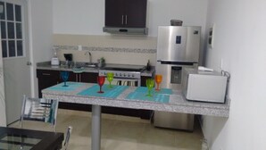 Une cuisine équipée d’un four à micro-ondes, d’une cuisinière et de placards. On peut y voir de la verrerie colorée posée sur le comptoir.