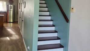 A staircase with white steps and a dark handrail, leading to a landing with a light green wall and a wooden ceiling. - Newly Renovated. Less than 5 minutes walk  to the Beach!!! Free Hi Speed WiFi!! (Nassau)