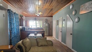 A cozy living room with a vintage sofa, a dining area with a table and chairs, a kitchen with a refrigerator, and a hallway with doors. - Newly Renovated. Less than 5 minutes walk  to the Beach!!! Free Hi Speed WiFi!! (Nassau)