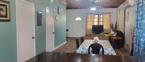 Un salón acogedor con techo de madera, una mesa de comedor con sillas, un sofá y una televisión.