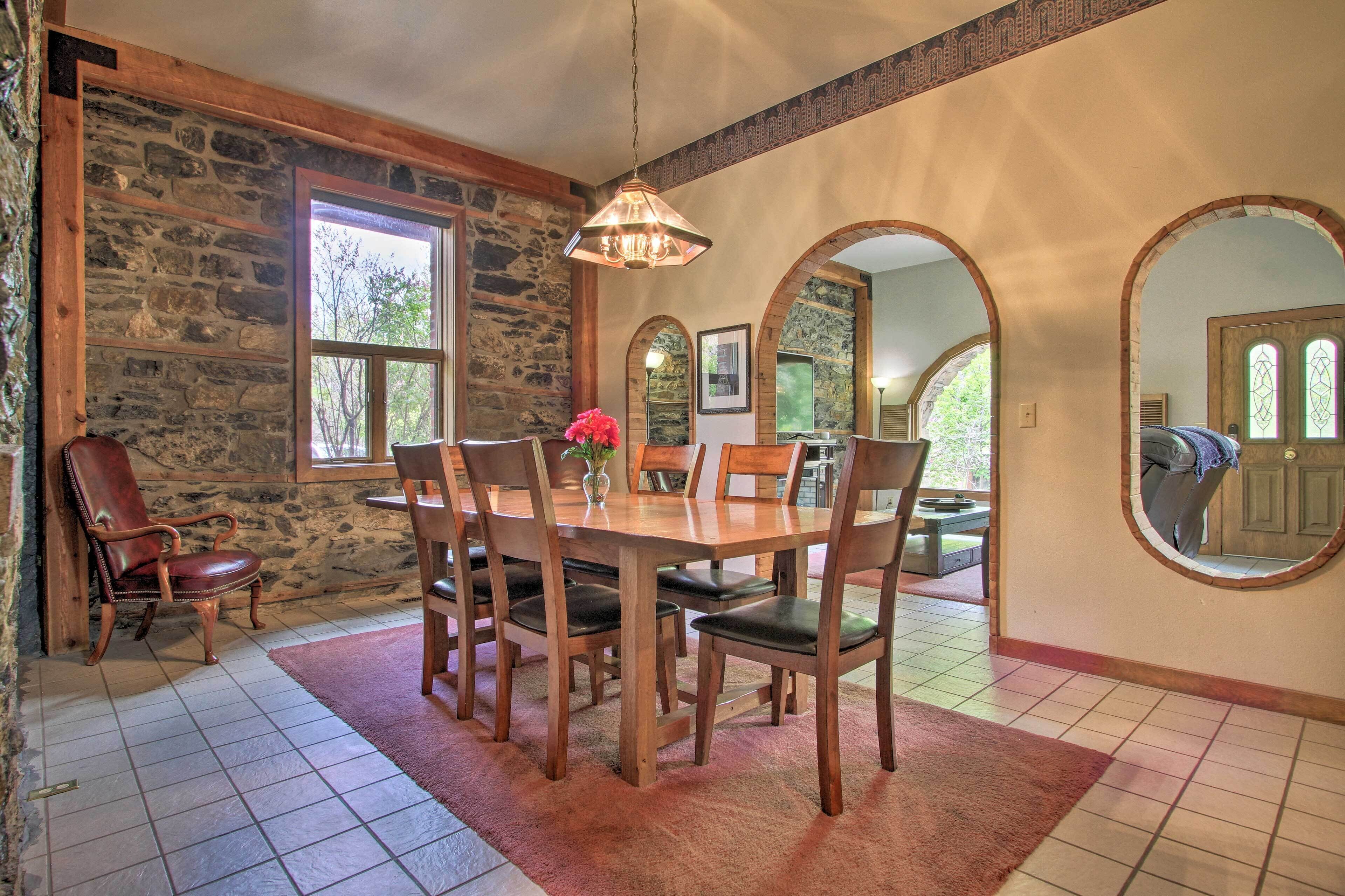 A dining area with a stone wall, wooden table, and chairs.
