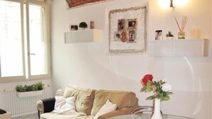 Ein modernes Wohnzimmer mit einem Glastisch, weißen Stühlen, einem beigen Sofa und einer Ziegeldecke.