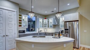 A modern kitchen with a large island, stainless steel appliances, and pendant lighting.