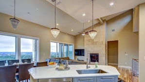 A modern kitchen with a large island, stainless steel appliances, and a view of the outdoors.