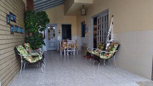 A covered patio area with outdoor seating, a tiled floor, and a potted plant. - Complete house in Praia do Rosa (Ibiraquera)