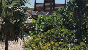 Una estructura de pérgola de madera con vistas a una playa y palmeras al frente.