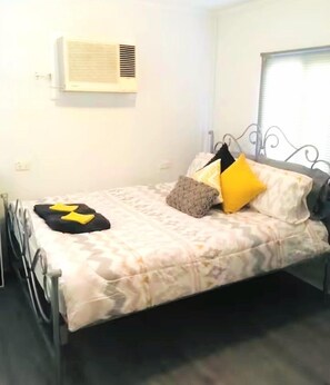 Un letto singolo con copriletto decorato, un cuscino e un cuscino ornamentale su una struttura in metallo.